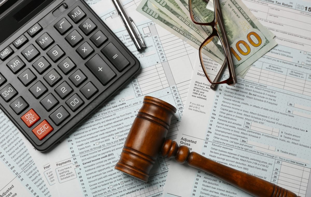 Judge gavel, money, calculator and eyeglasses on tax forms